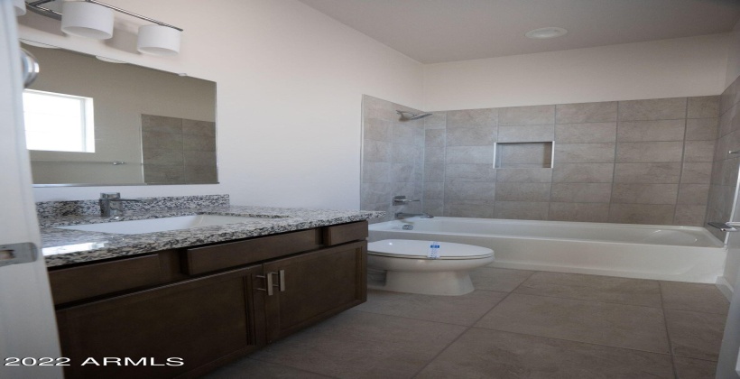 Full bathroom with granite counter.