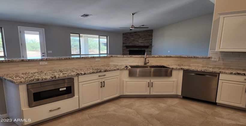 ACTUAL PICTURE OF THE OPEN KITCHEN WITH WHITE CABINETS, BUILT IN MICROWAVE, FARMER SINK & DISHWASHER, GRANITE COUNTER TOPS