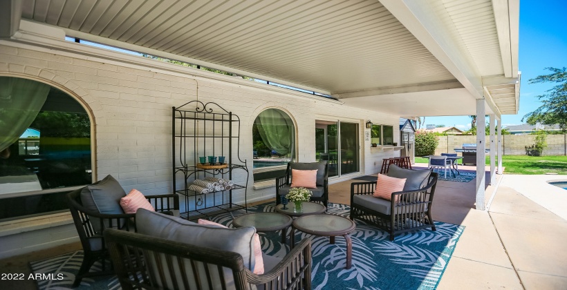 The backyard area includes plenty of space to relax, a dining table, BBQ grill, and a breakfast bar.