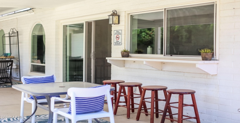 The backyard area includes plenty of space to relax, a dining table, BBQ grill, and a breakfast bar.