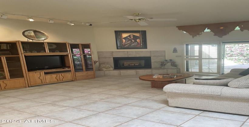 Spacious living area with wood burning fireplace, doors to patio bringing the outdoors in.