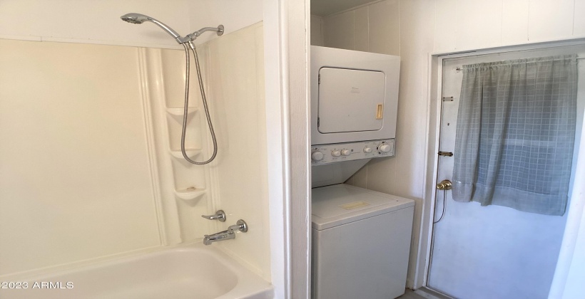 Full bathroom with tub and shower and stacked washer and dryer included in purchase