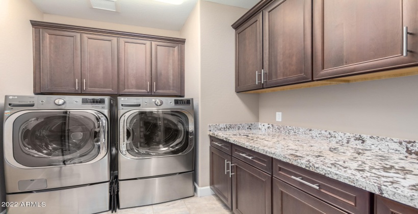 Large laundry room with extra cabinetry and granite countertops