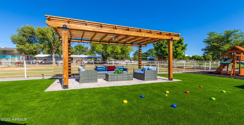 Ramada surrounded by turf overlooking pool, play structure and animal pastures.